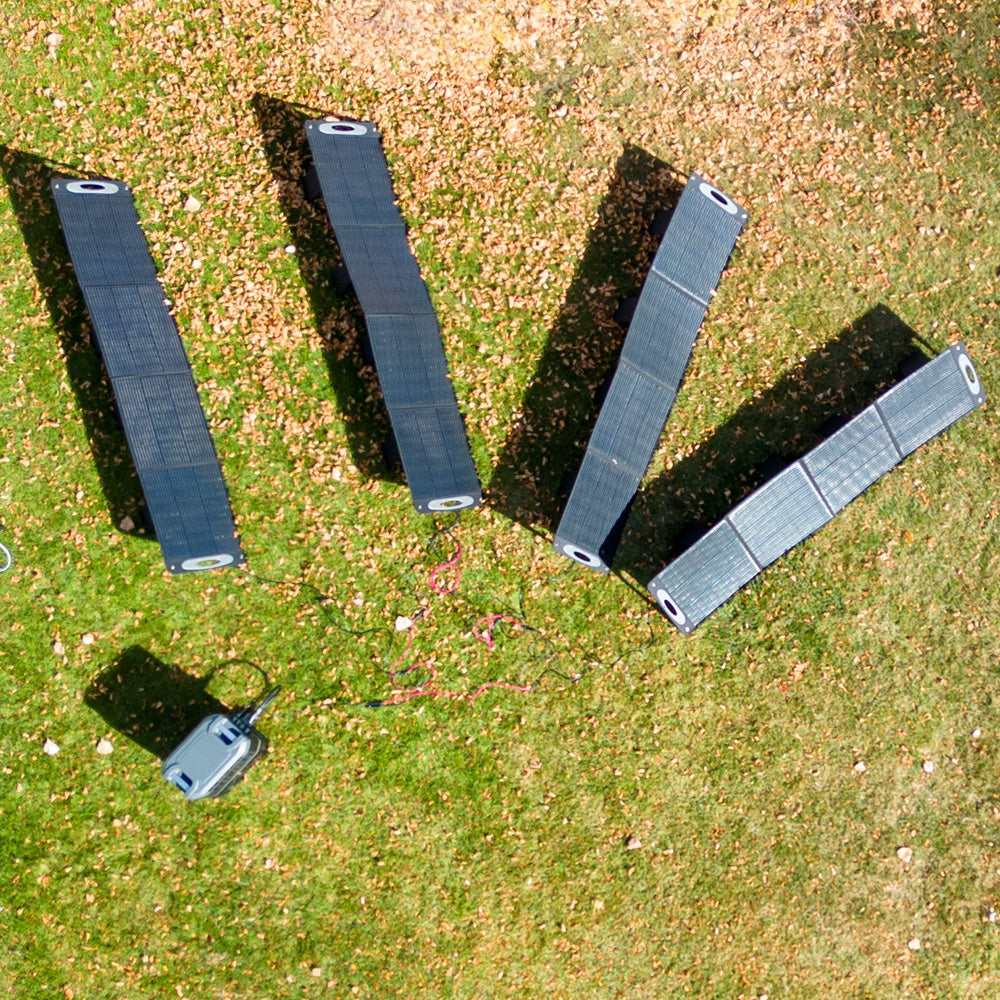 Quartet of Grid Doctor 200W Solar Panels aligned on green grass, soaking up the sun's energy, showcasing the panel's adaptability and performance in an outdoor environment.