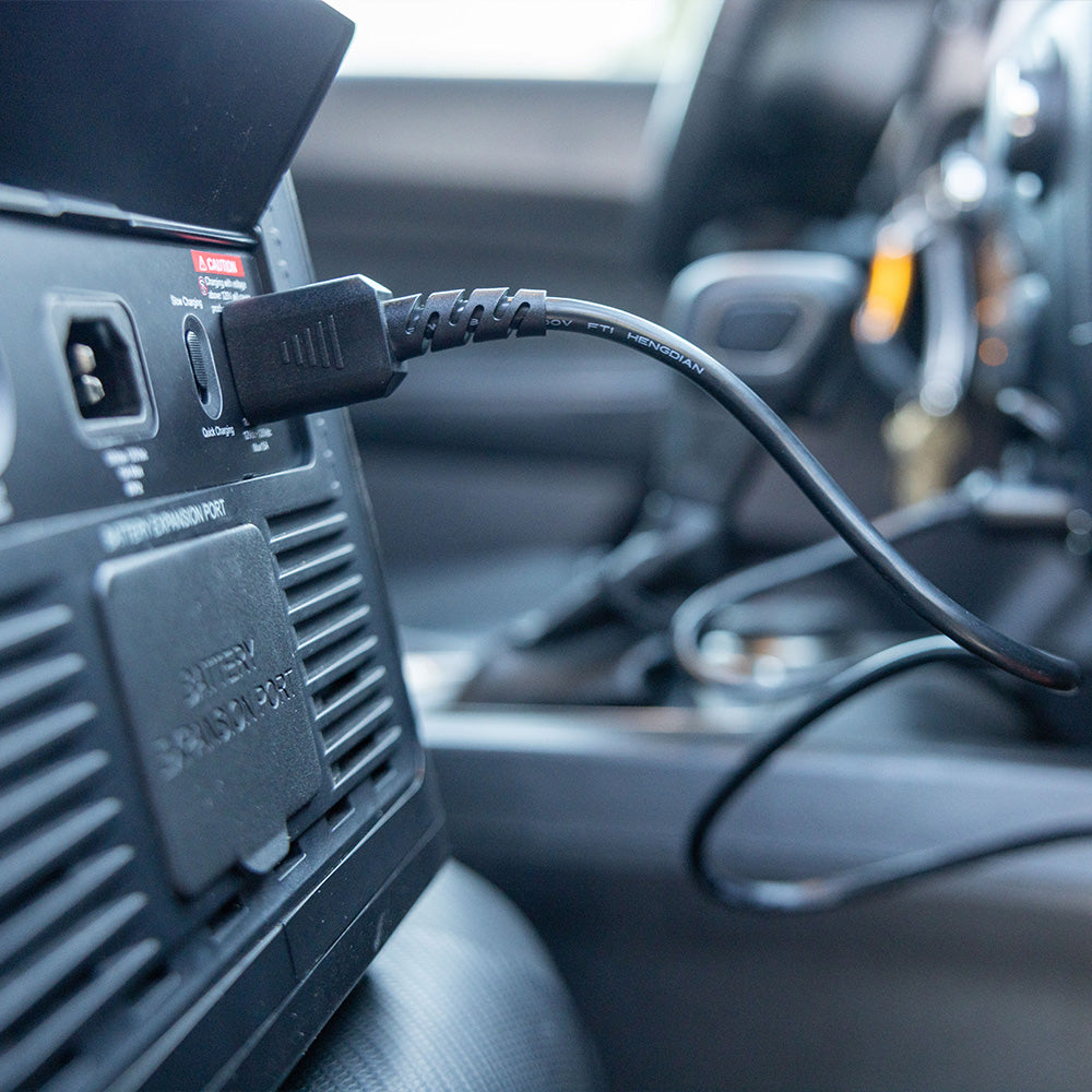 Grid Doctor 2200 system connected to a car's charging port, demonstrating the system's versatility in recharging from an automotive power source.