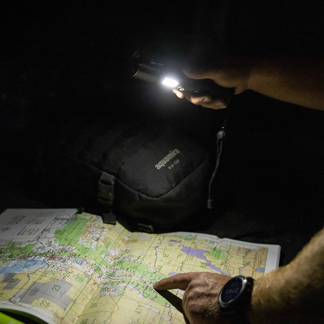 Person using Grid Doctor Survival 1K-LM Flashlight to read a map at night